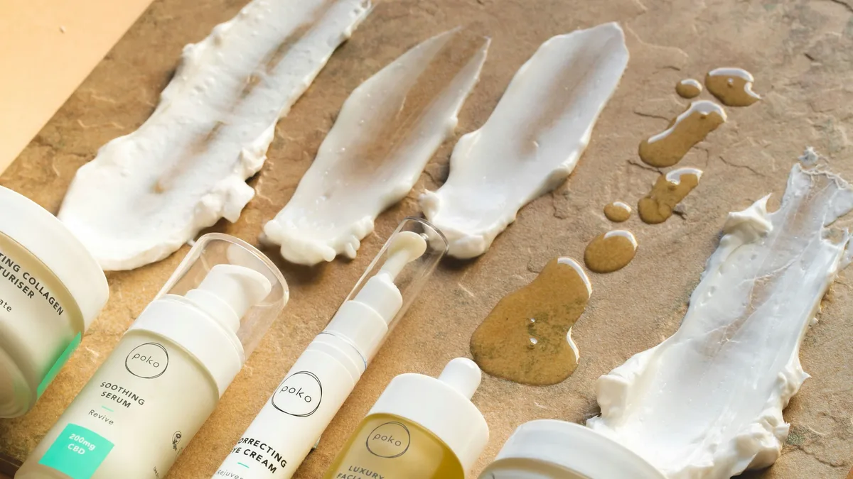 A collection of skincare products, including bottles and jars, with some of the products smeared or spread out on a surface.